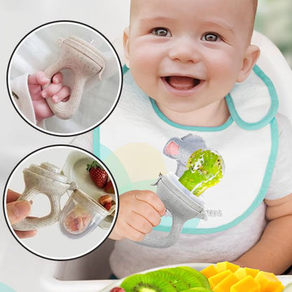 Bébé en chaise haute tenant une grignoteuse silicone grise avec kiwi et mangue – poignée ergonomique premiers aliments