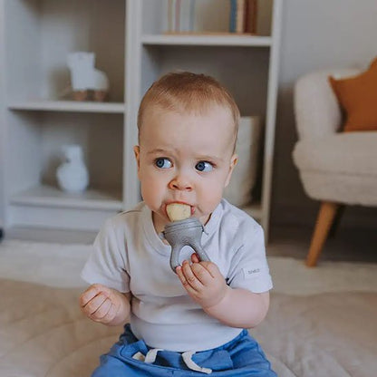 Bébé garçon qui grignote un aliment solide avec une grignoteuse à poche perforée – diversification alimentaire
