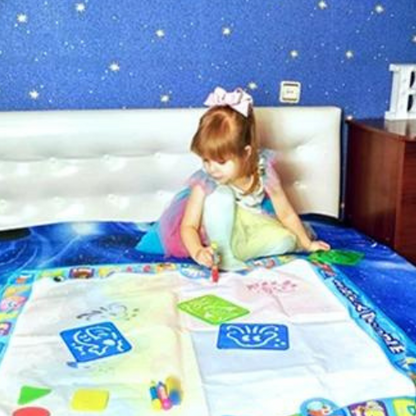Enfant dessinant tranquillement sur tapis magique à l'eau
